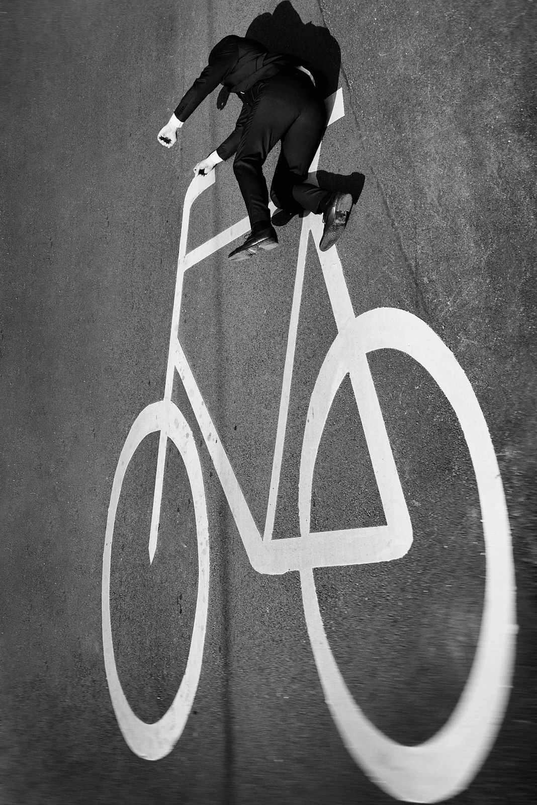 A person lying on the ground next to a bicycle street marking painted on the pavement.