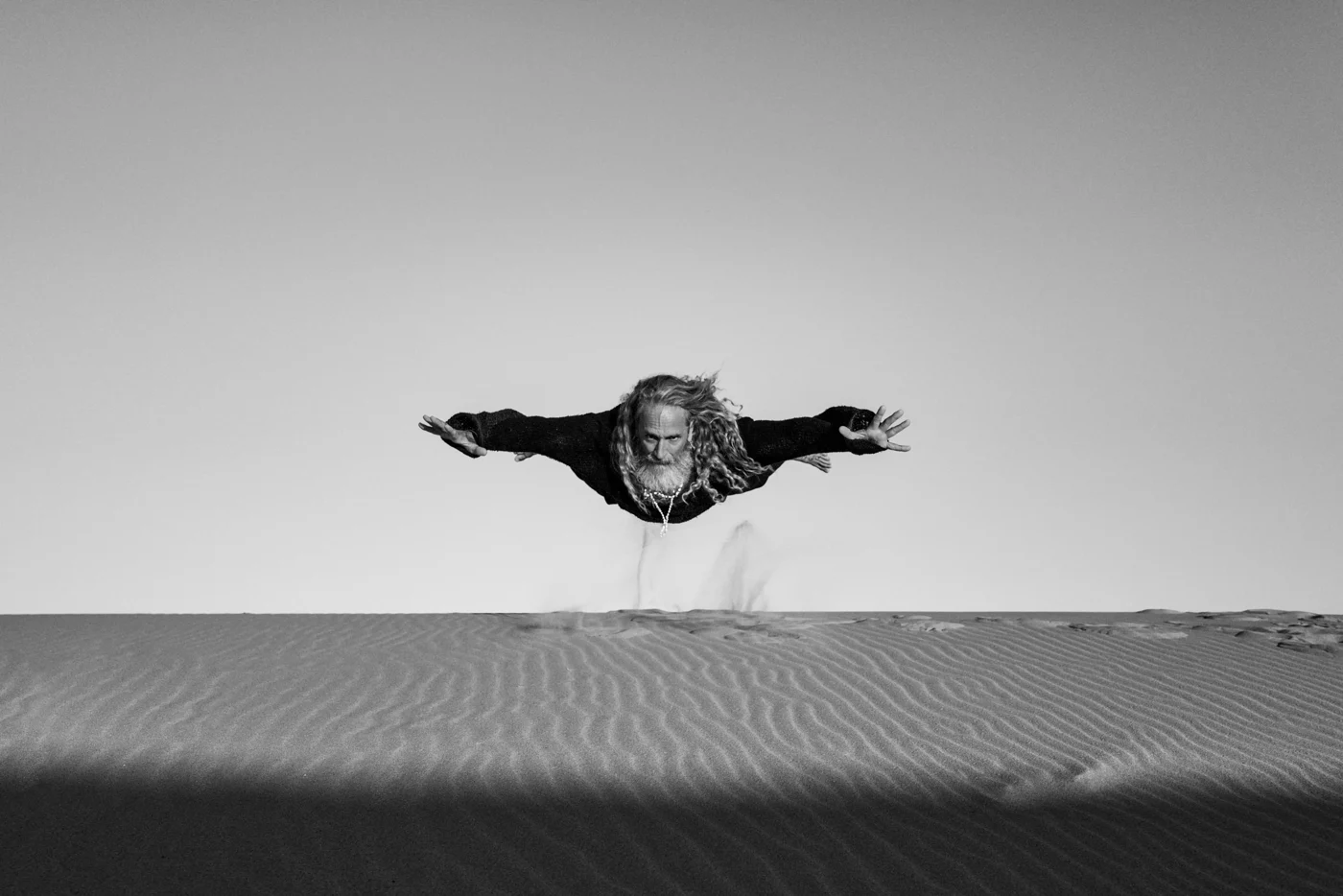 A figure appearing to float horizontally above a quiet shoreline.