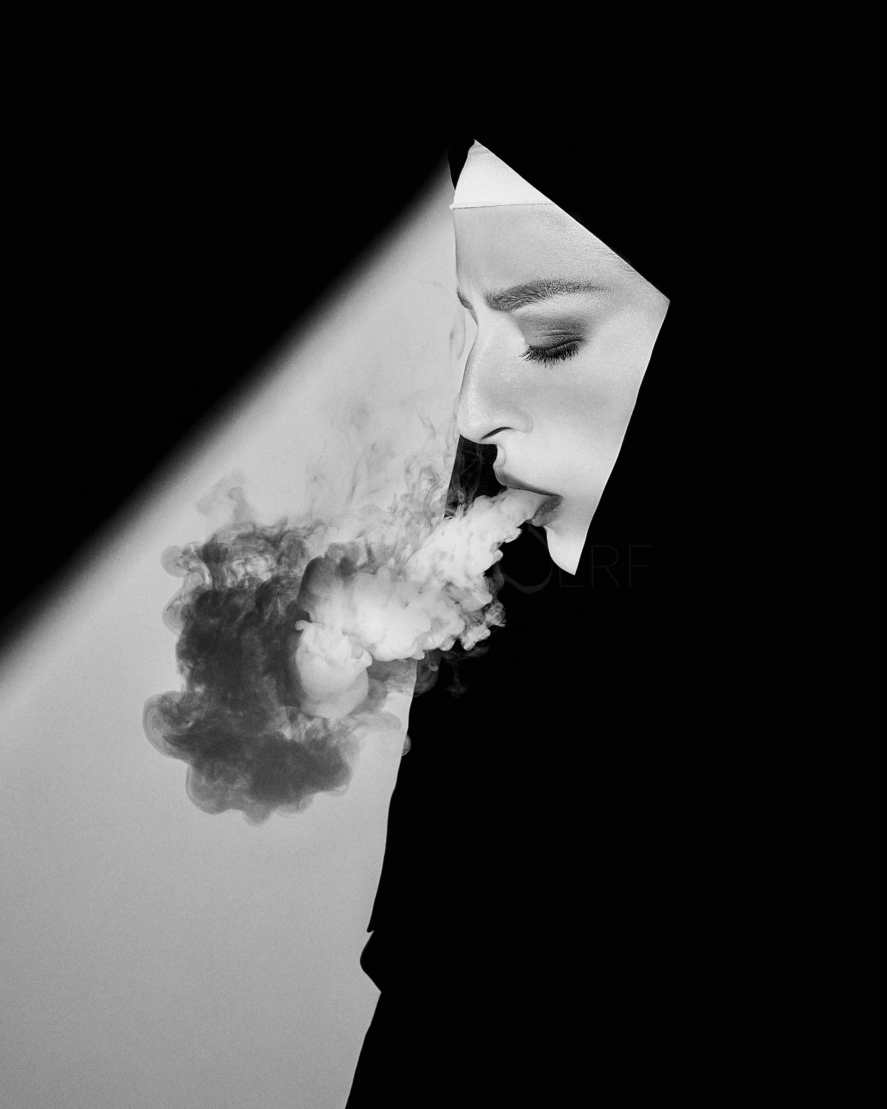 A bearded man in profile, his face cut by a narrow geometric beam of light.