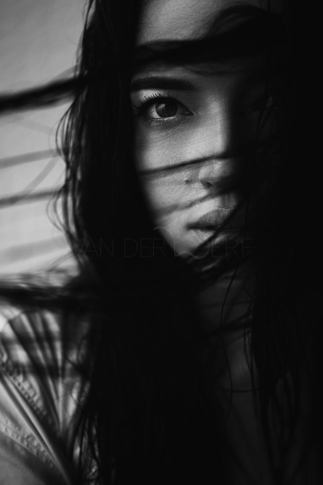 A close portrait with strands of dark hair crossing a woman's face.