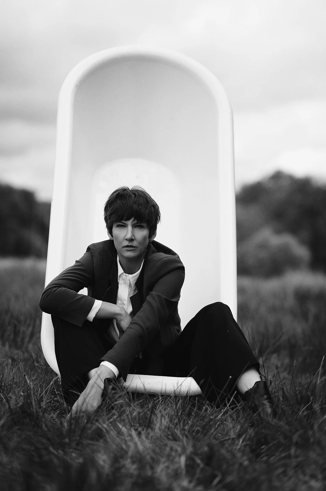 A man in a dark suit sitting in a white chair outdoors.