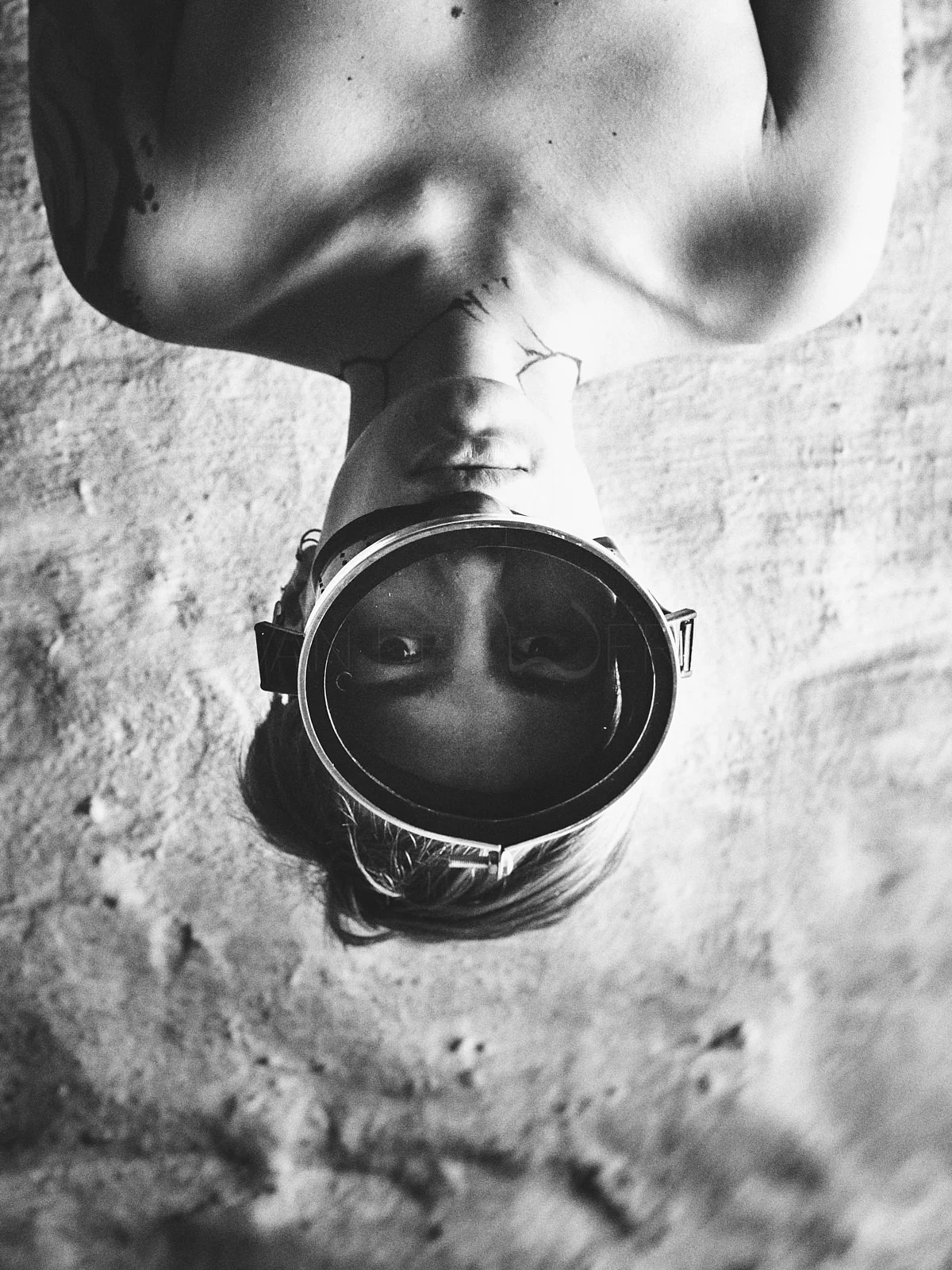 An upside-down portrait using a round mirror on a textured wall.