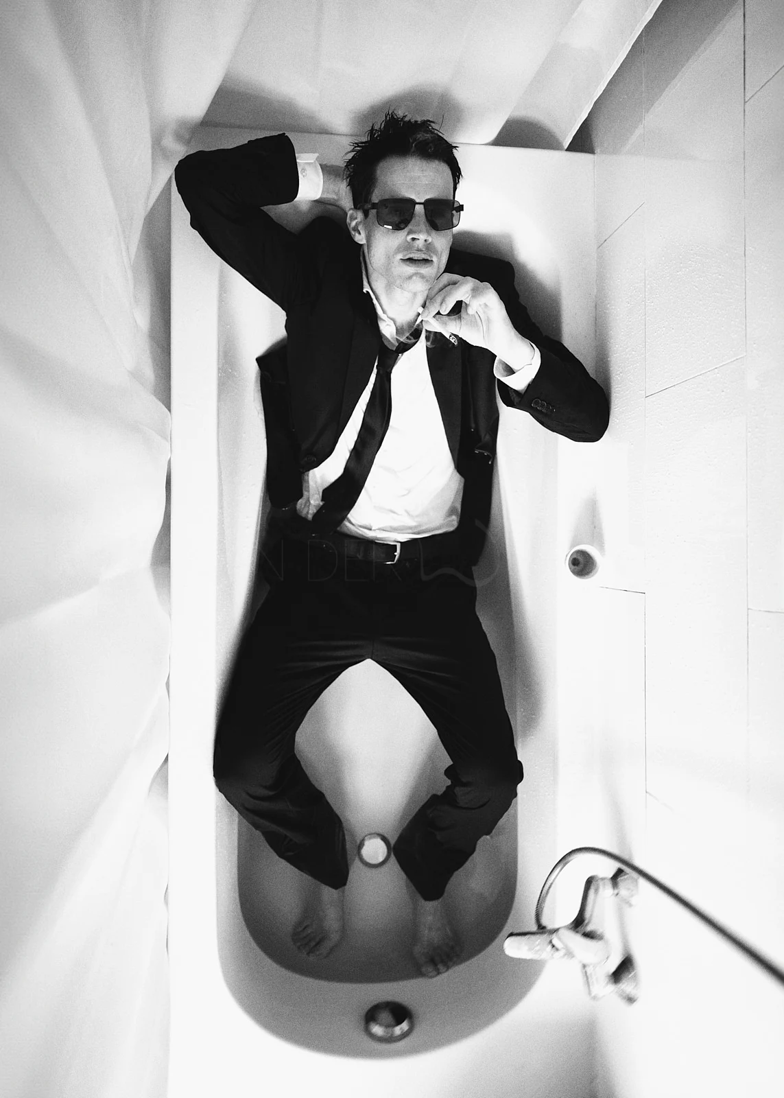 A man in a suit posing inside a bathtub.