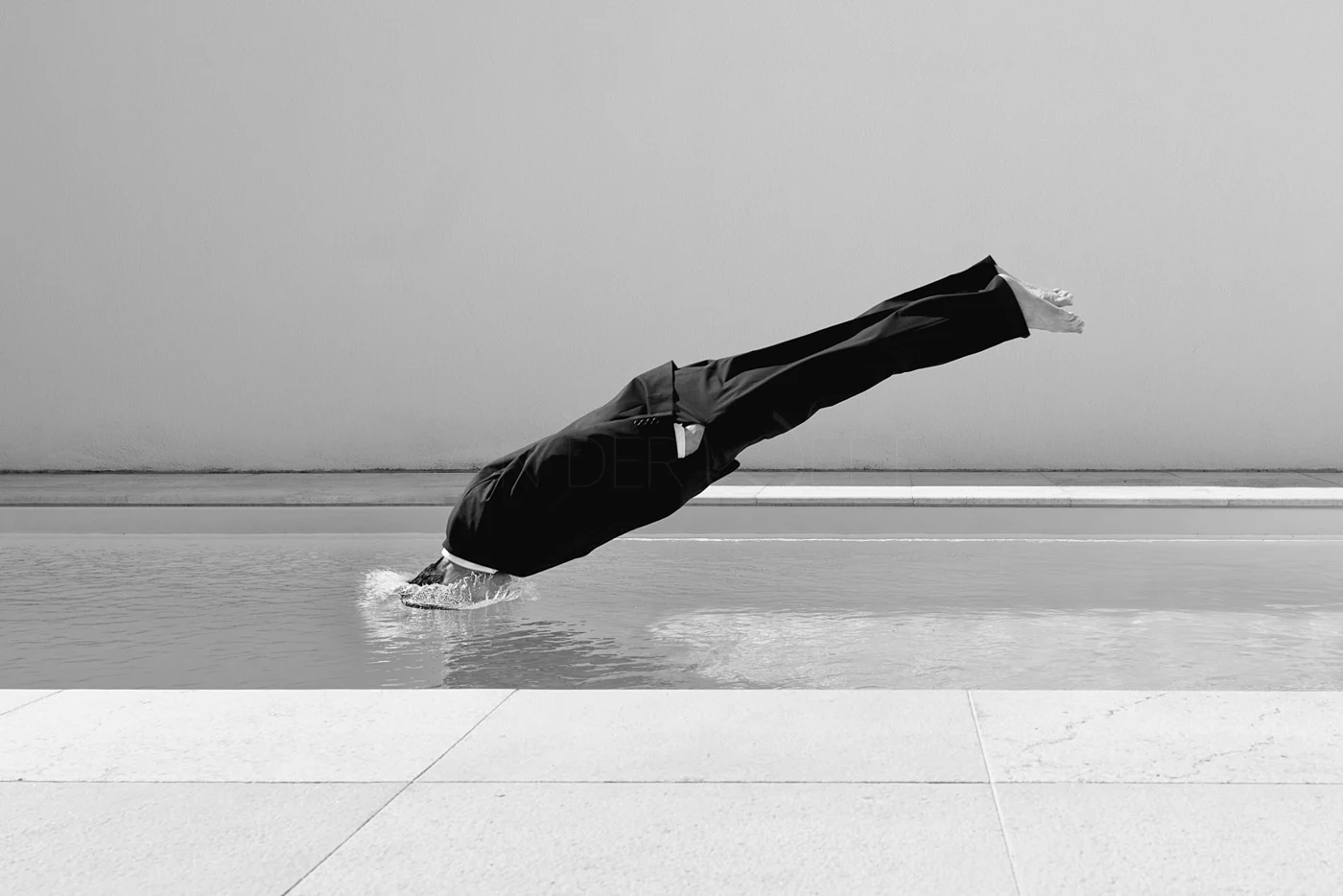 A person appearing to hover horizontally above a still body of water.
