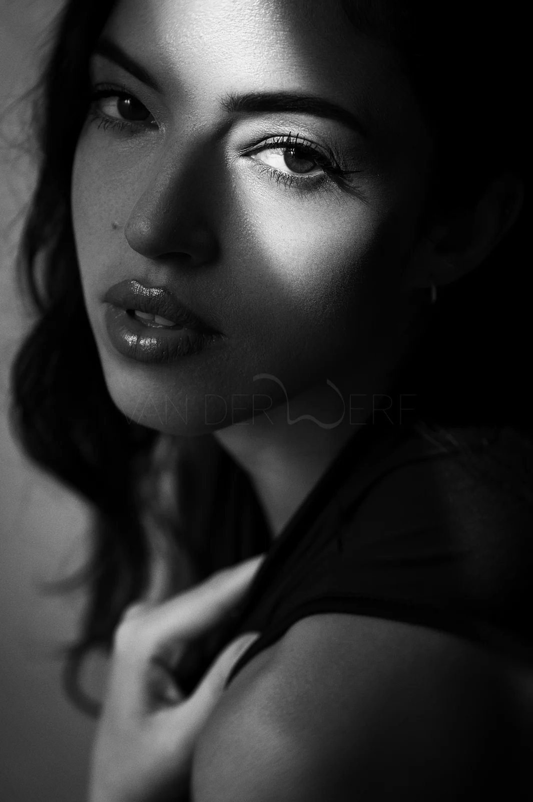 A woman looking towards the camera, a band of light crossing her face.