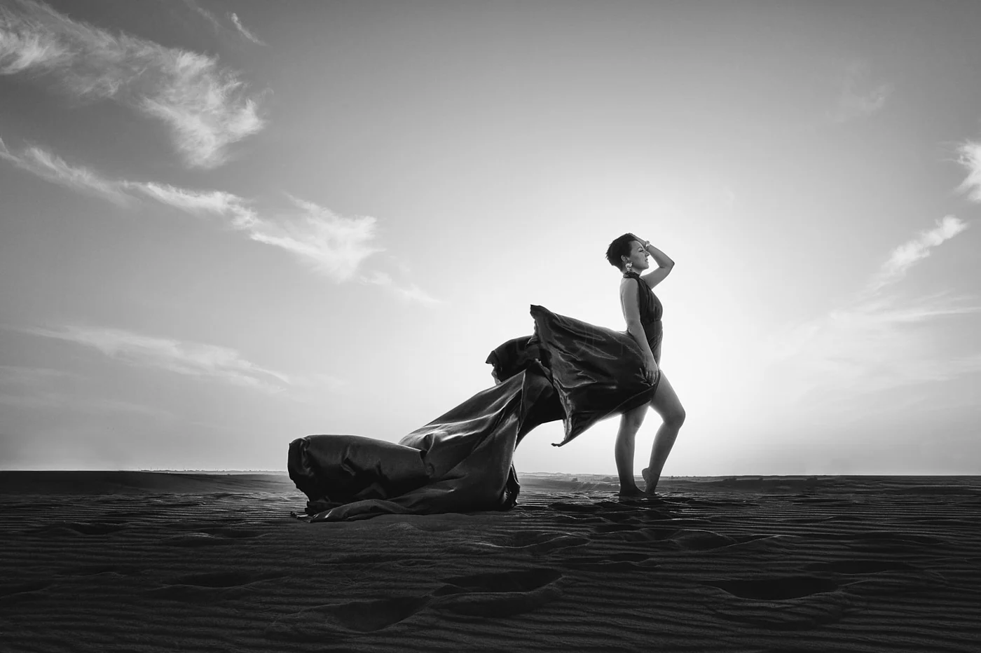 A person leaning back on a sandy dune beneath an open sky.