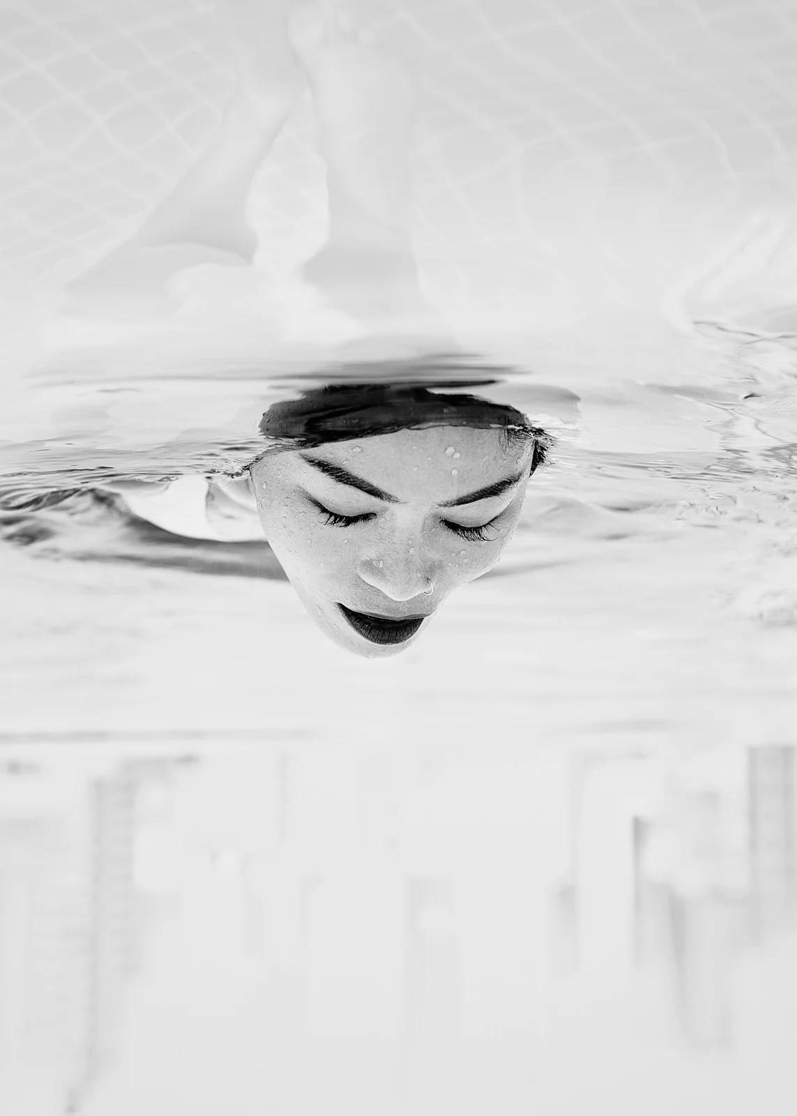 A face seen through and reflected in pale water.