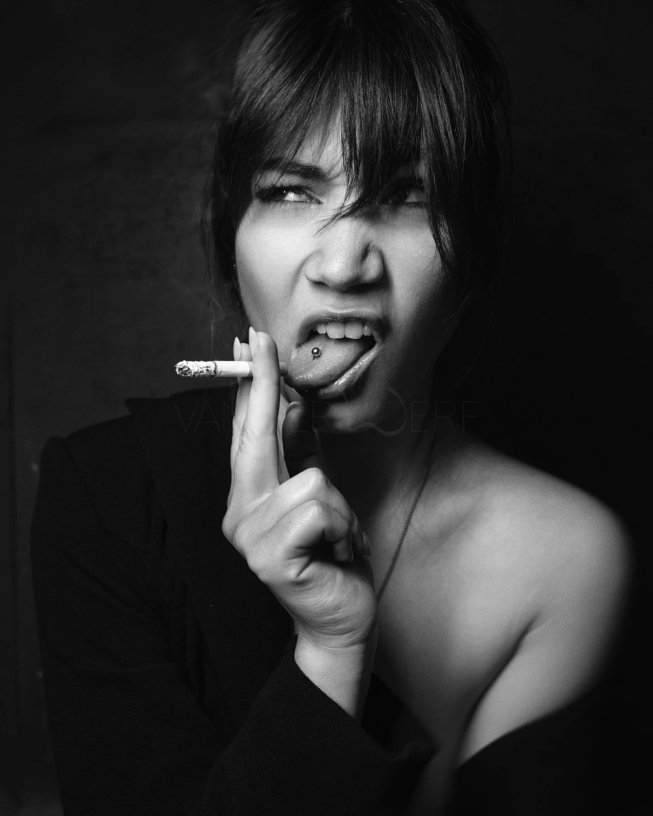 A short-haired woman making a playful expression with a cigarette near her mouth.