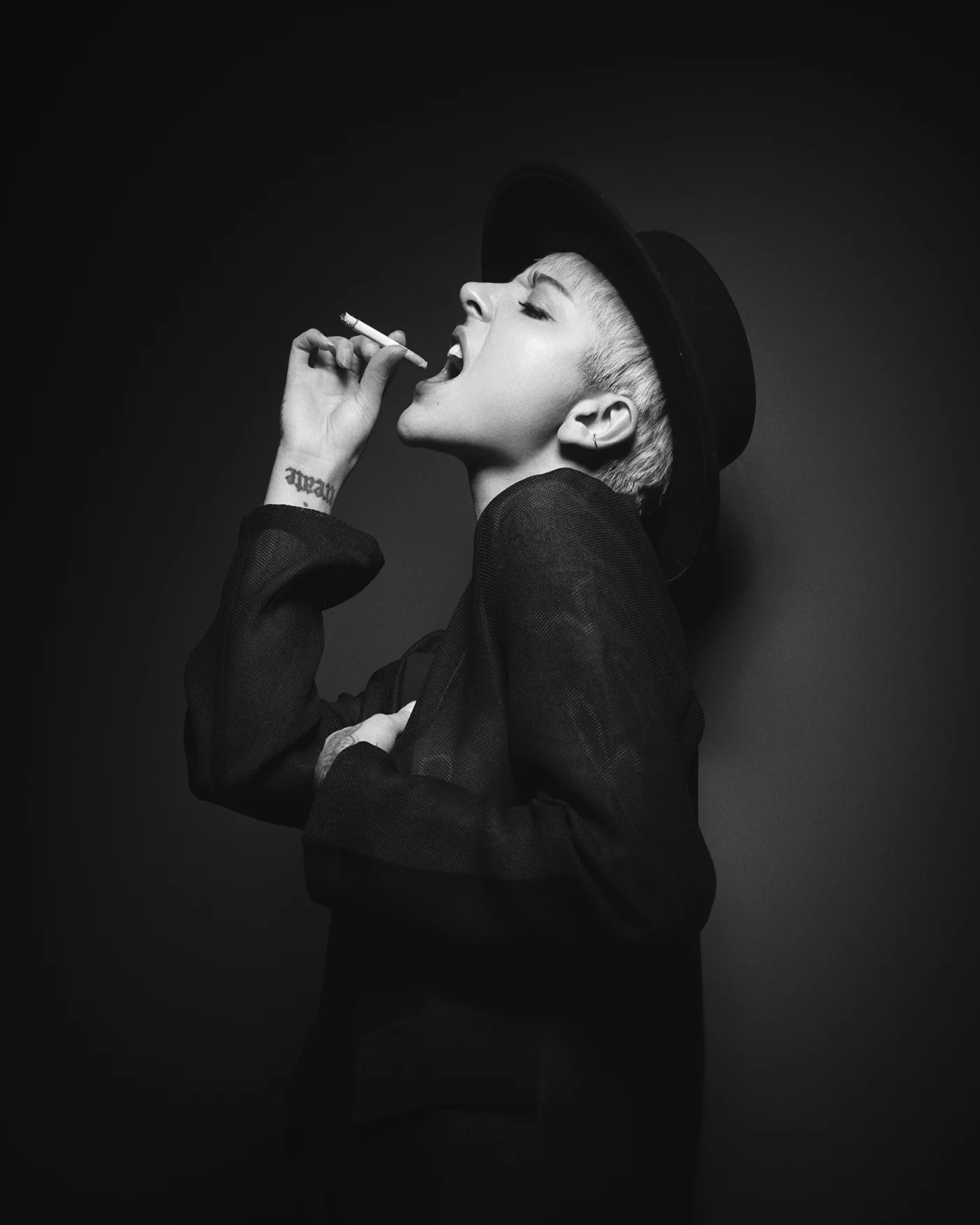 A woman in a dark hat and blazer looking upwards.