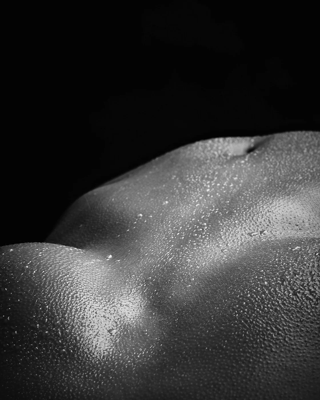 Close-up of a human torso with water droplets on the skin, black background