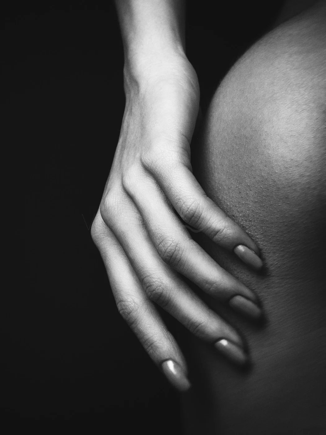 Close-up black and white photo of a hand with long fingernails resting on a person's shoulder.