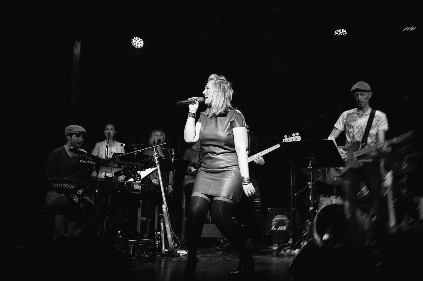 A female singer performing on stage with a band, black and white photo