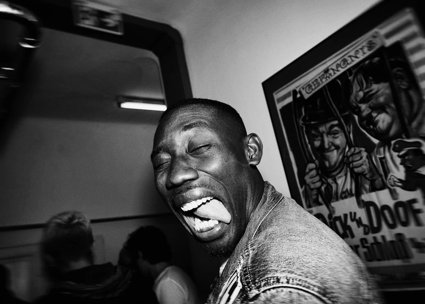 Black and white photo of a man making a funny face with his tongue out and eyes closed.