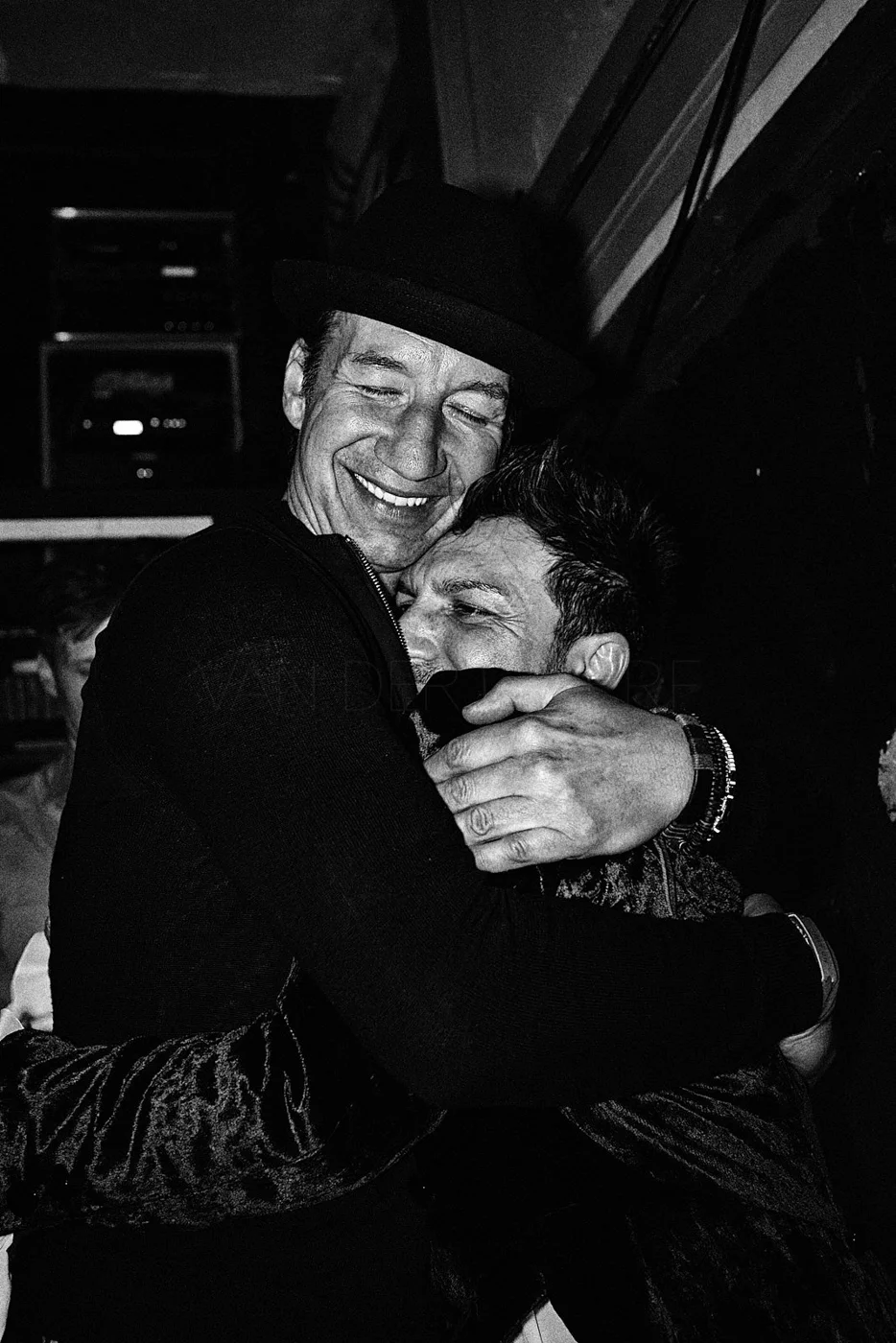 Two men sharing an emotional hug, smiling and showing affection, in a joyful moment.
