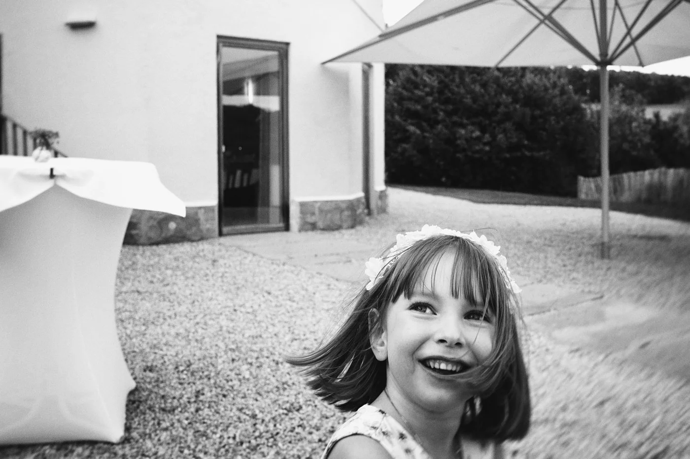 A young girl with a flower crown smiling outdoors in black and white