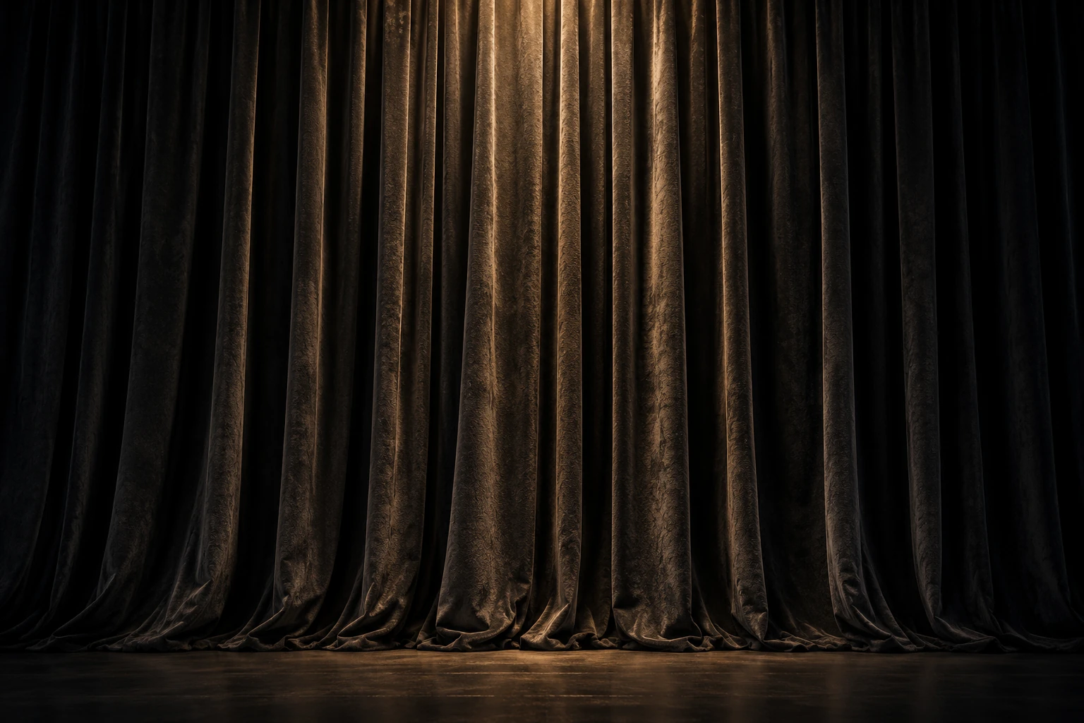A closed charcoal velvet curtain in soft warm stage light.