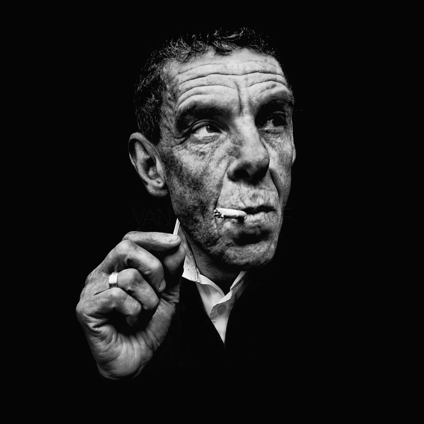 Black and white portrait of a man with a cigarette in his mouth, looking thoughtful.