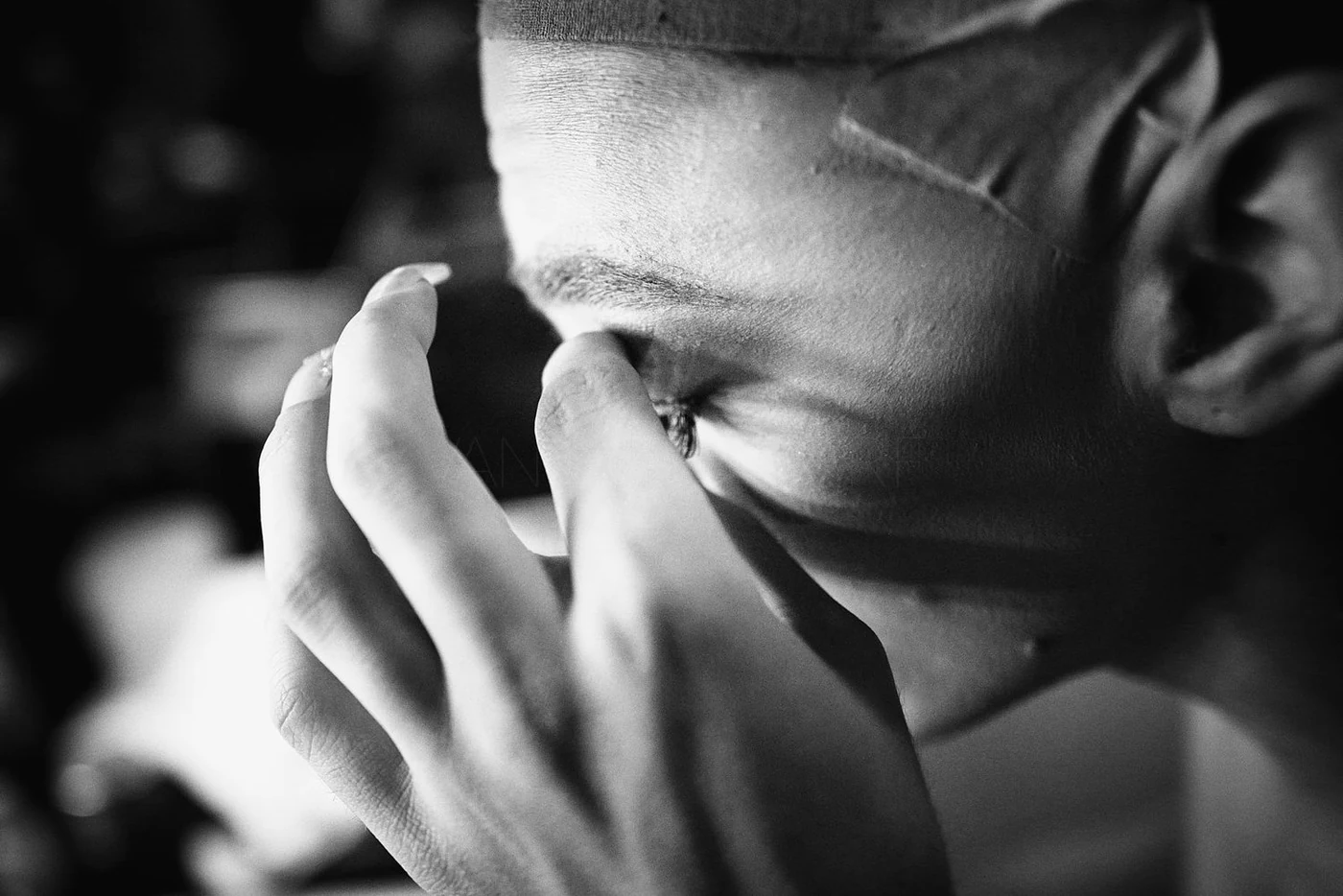 Close-up black and white photo of a woman pinching her nose with her fingers, with emotional expression.