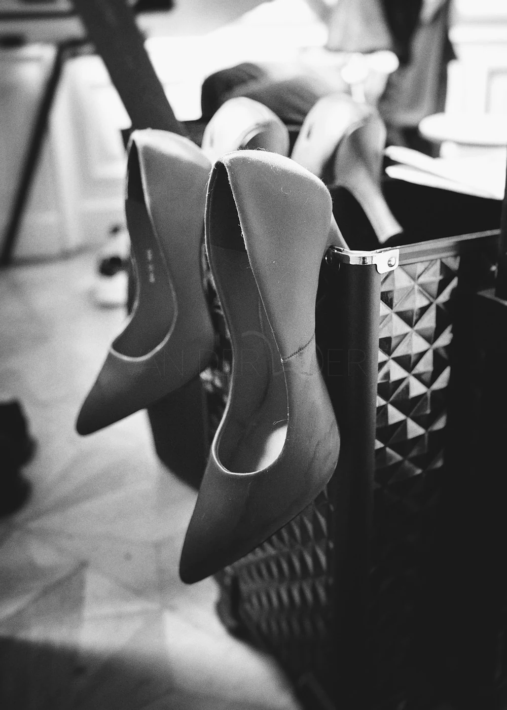 A black and white photo of high-heeled shoes hanging on a rack in a room.