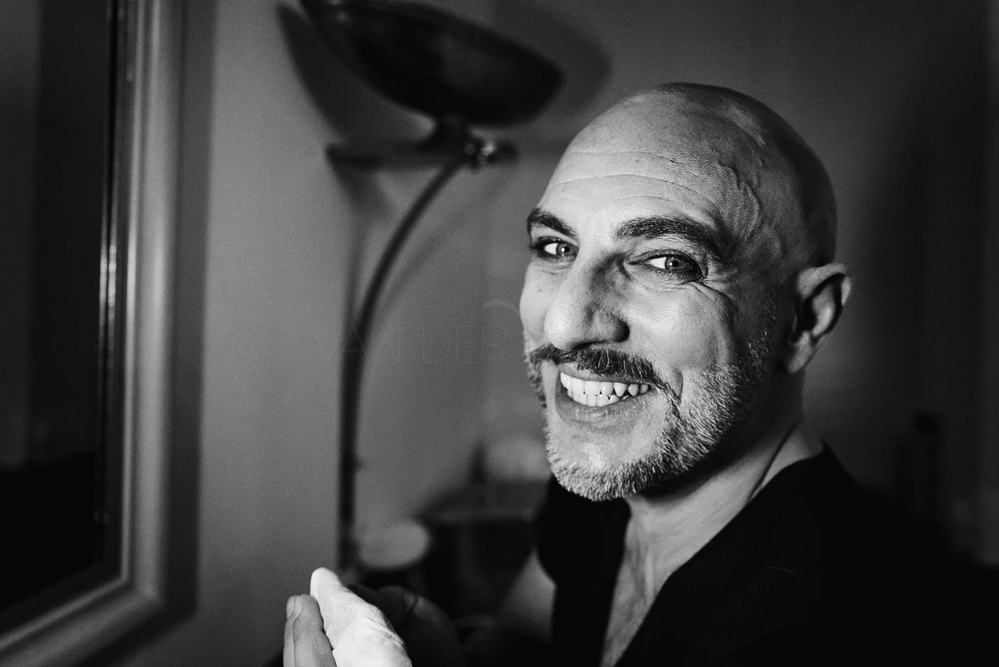 A smiling, bald man with a beard in black and white, looking at the camera.
