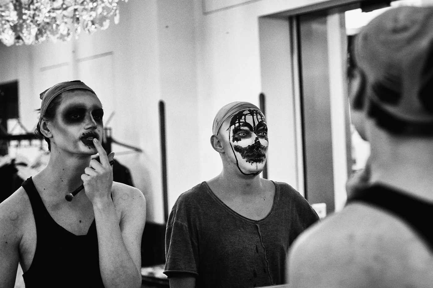Three people with clown makeup and costumes preparing for a performance in a backstage area.