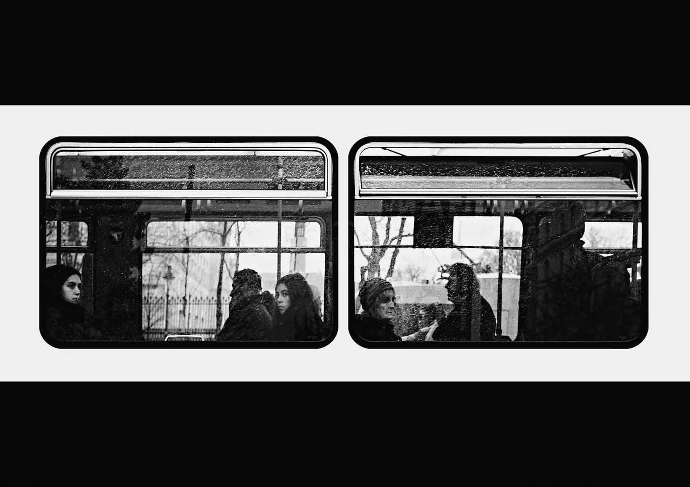 Black and white photo of people sitting inside a train, seen through the windows, with reflections and outdoor scenery visible.