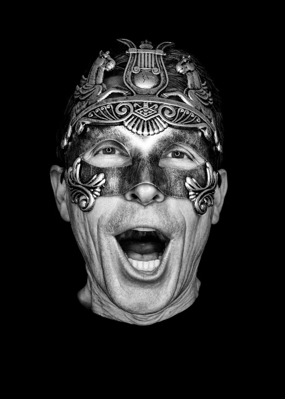 Person wearing a decorative mask with open mouth, dark background.